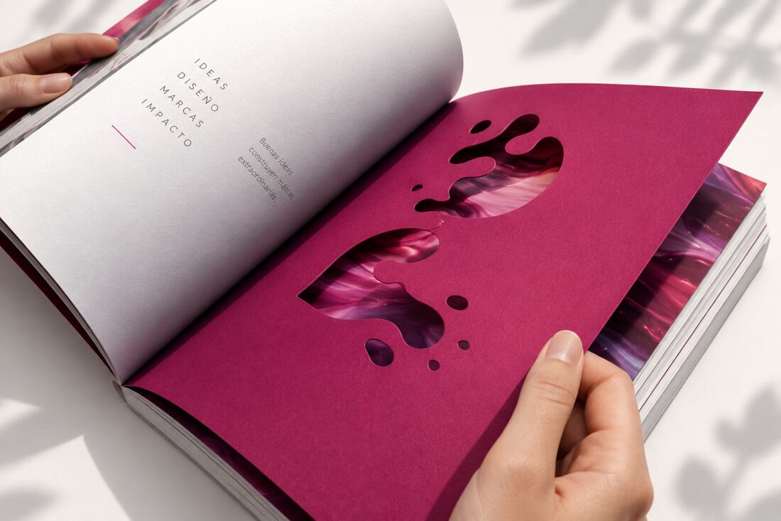 Libro editorial abierto con papel magenta troquelado y diseño de Inkspira
